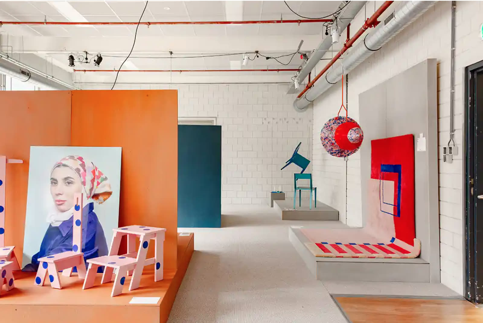 Gallery corner with orange plinths and prototype furniture